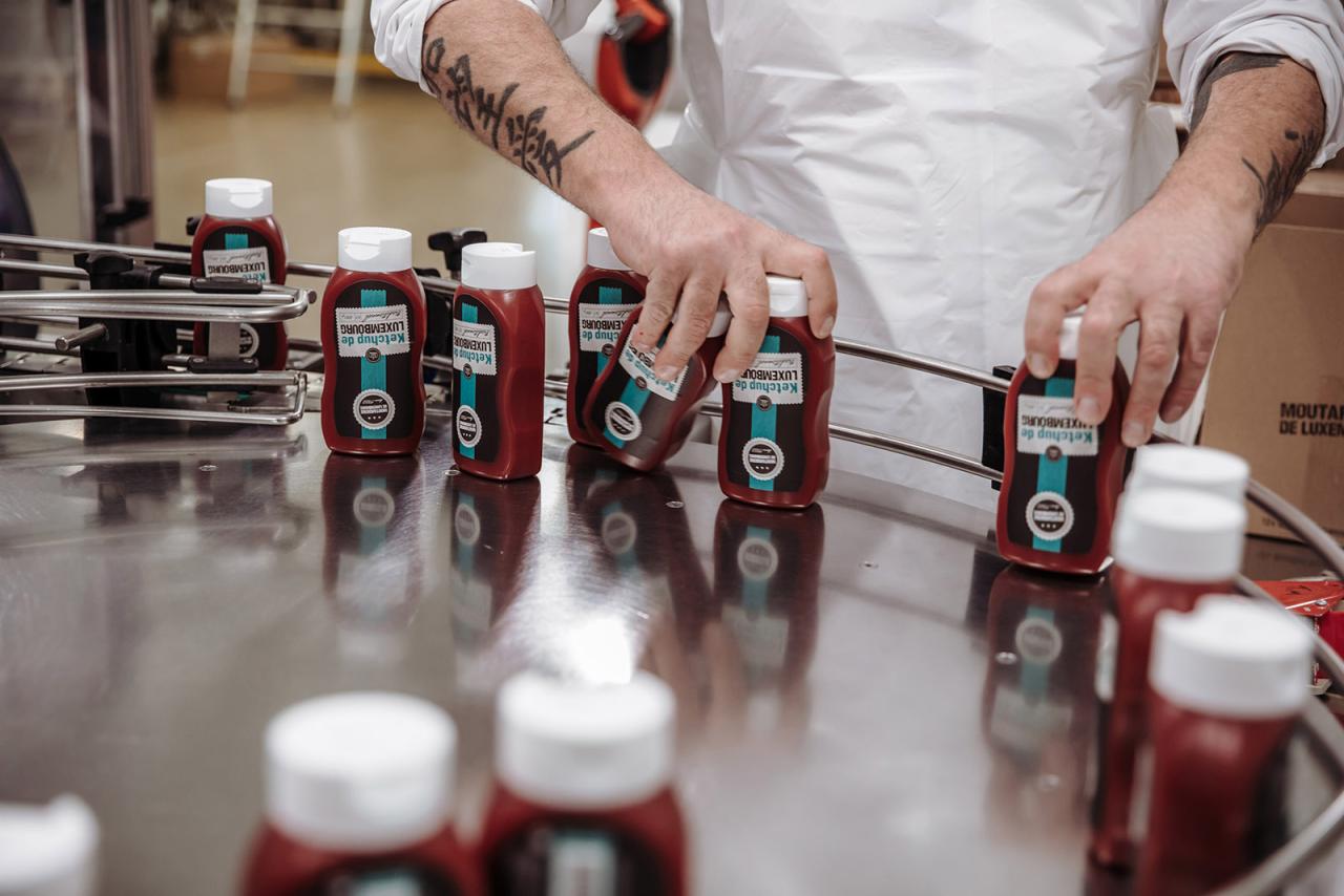 Des bouteilles de ketchup sont prises par un employé