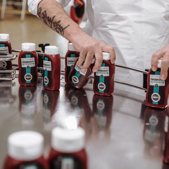 Des bouteilles de ketchup sont prises par un employé